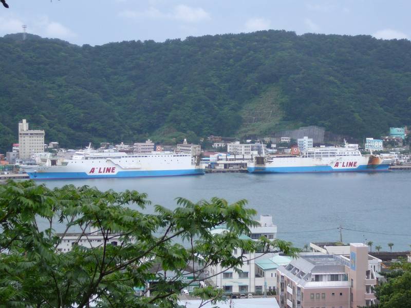 奄美市名瀬の港に並んで停泊する大型フェリーと、背後の緑の山